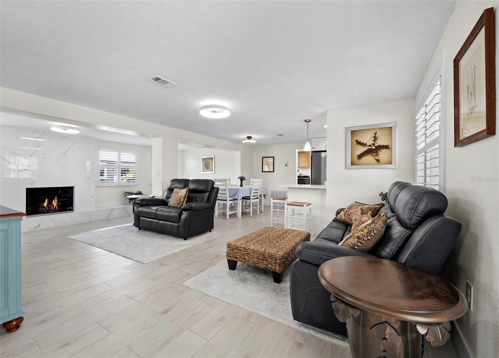 An open-concept living and dining area features white tile floors, a marble fireplace, and furniture — 726 JUNGLE QUEEN WAY, LONGBOAT KEY, FL