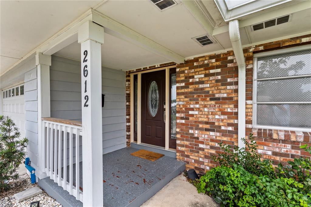 A front porch features a brick facade, a brown front door, and a white railing — 2612 TIMBERLAKE DRIVE, ORLANDO, FL