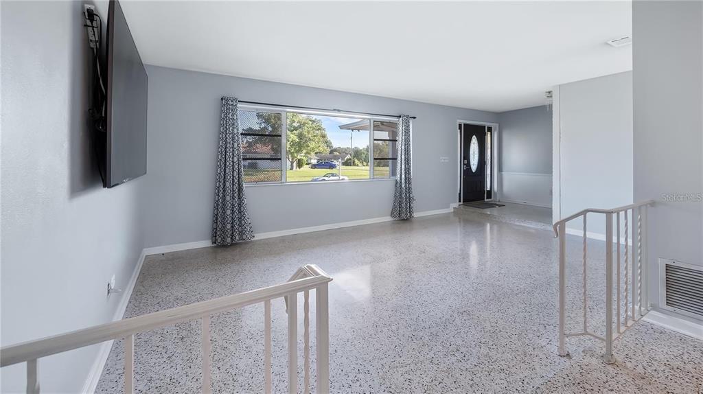 A living room with light gray walls, terrazzo flooring, and a large window with curtains — 2612 TIMBERLAKE DRIVE, ORLANDO, FL
