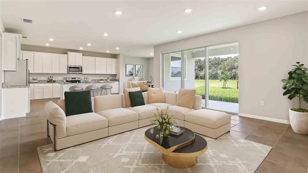 An open-concept living room and kitchen with white cabinetry, tile floors, and sliding glass doors — 3516 HAZY GLEN LANE, PLANT CITY, FL