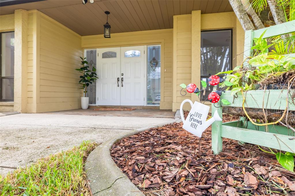 A front entryway features double white doors, a concrete porch, and a decorative garden sign — 4415 MARINE PARKWAY, NEW PORT RICHEY, FL