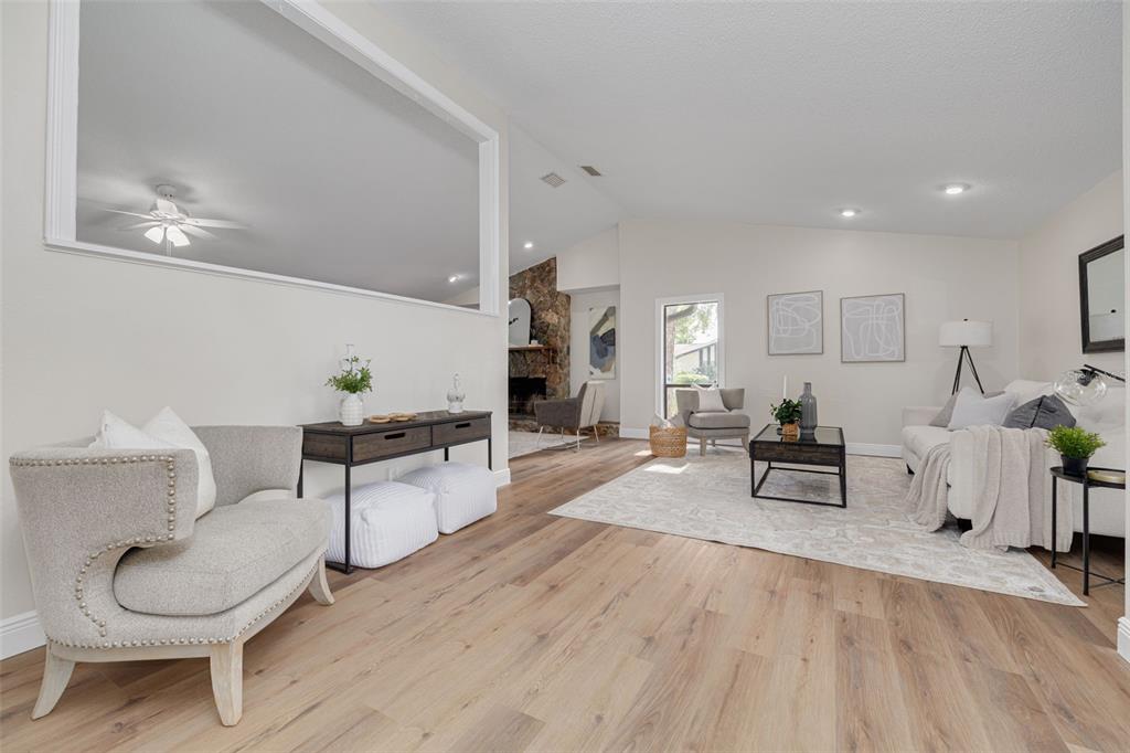 A living room features light wood flooring, a stone fireplace, and neutral-toned furniture — 4415 MARINE PARKWAY, NEW PORT RICHEY, FL