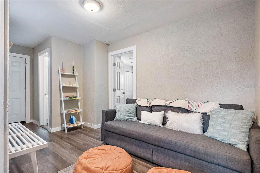 A living room features a gray sofa, a white ladder shelf, and wood-look flooring — 623 MOUND PARK WAY S, ST PETERSBURG, FL