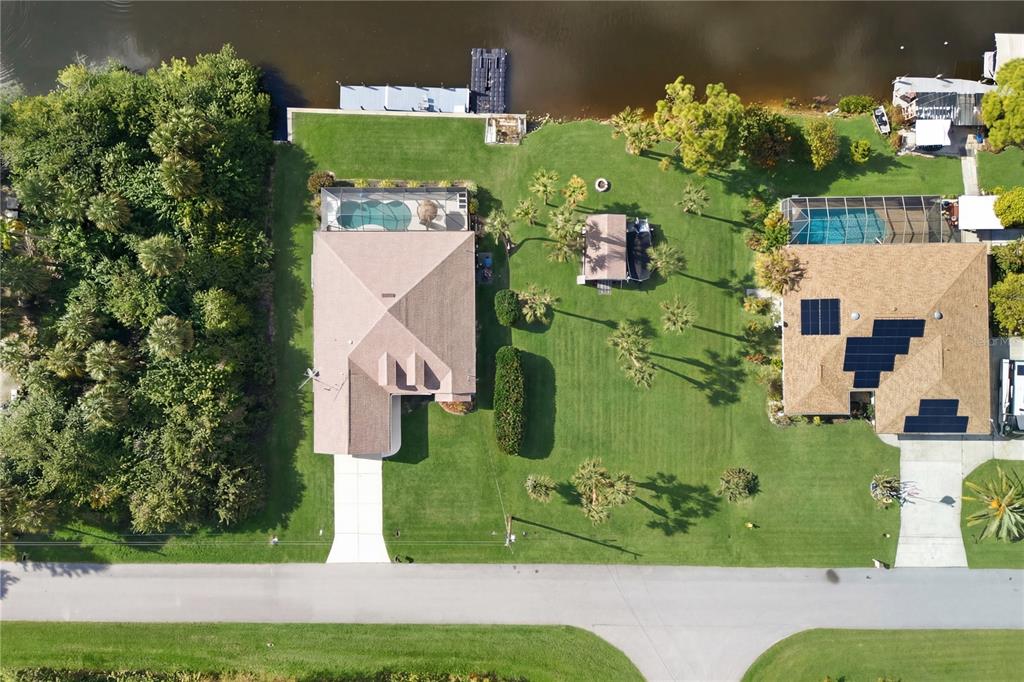 An aerial view shows two waterfront houses with swimming pools, large lawns, and private docks — 361 CHESHIRE STREET, PORT CHARLOTTE, FL