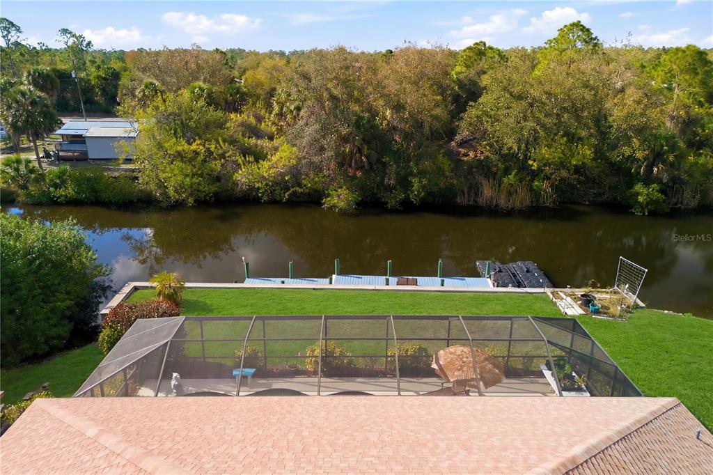 An aerial view shows a screened-in pool patio, a grassy lawn, and a canal dock — 361 CHESHIRE STREET, PORT CHARLOTTE, FL
