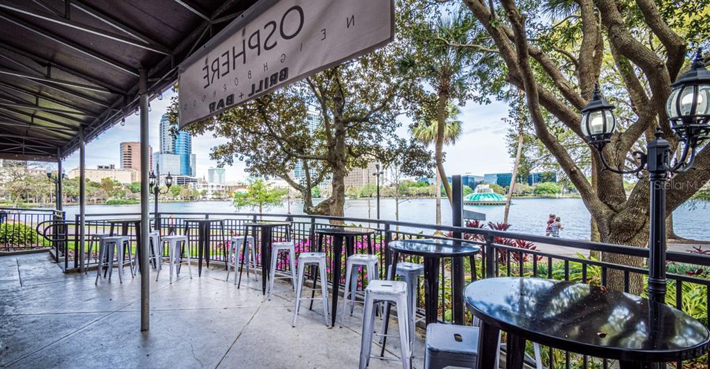 An outdoor patio with high-top tables and stools overlooks a lake and city skyline — 407 E CENTRAL BOULEVARD, ORLANDO, FL