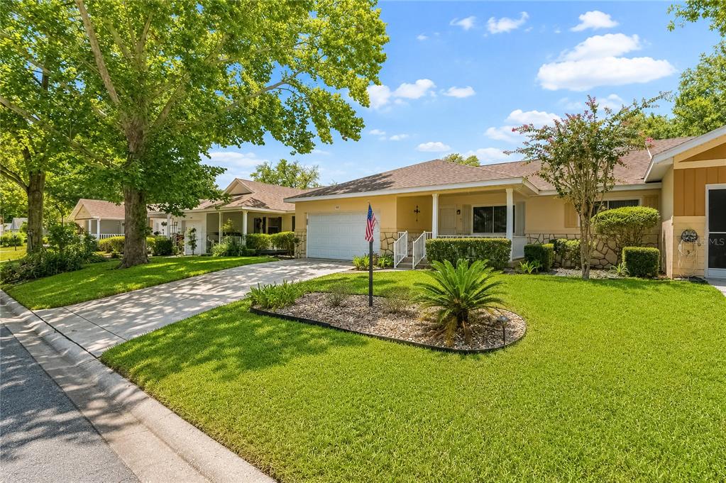 A single-story house with a beige exterior, a two-car garage, and a landscaped front yard — 8702 SW 94TH STREET UNIT E, OCALA, FL