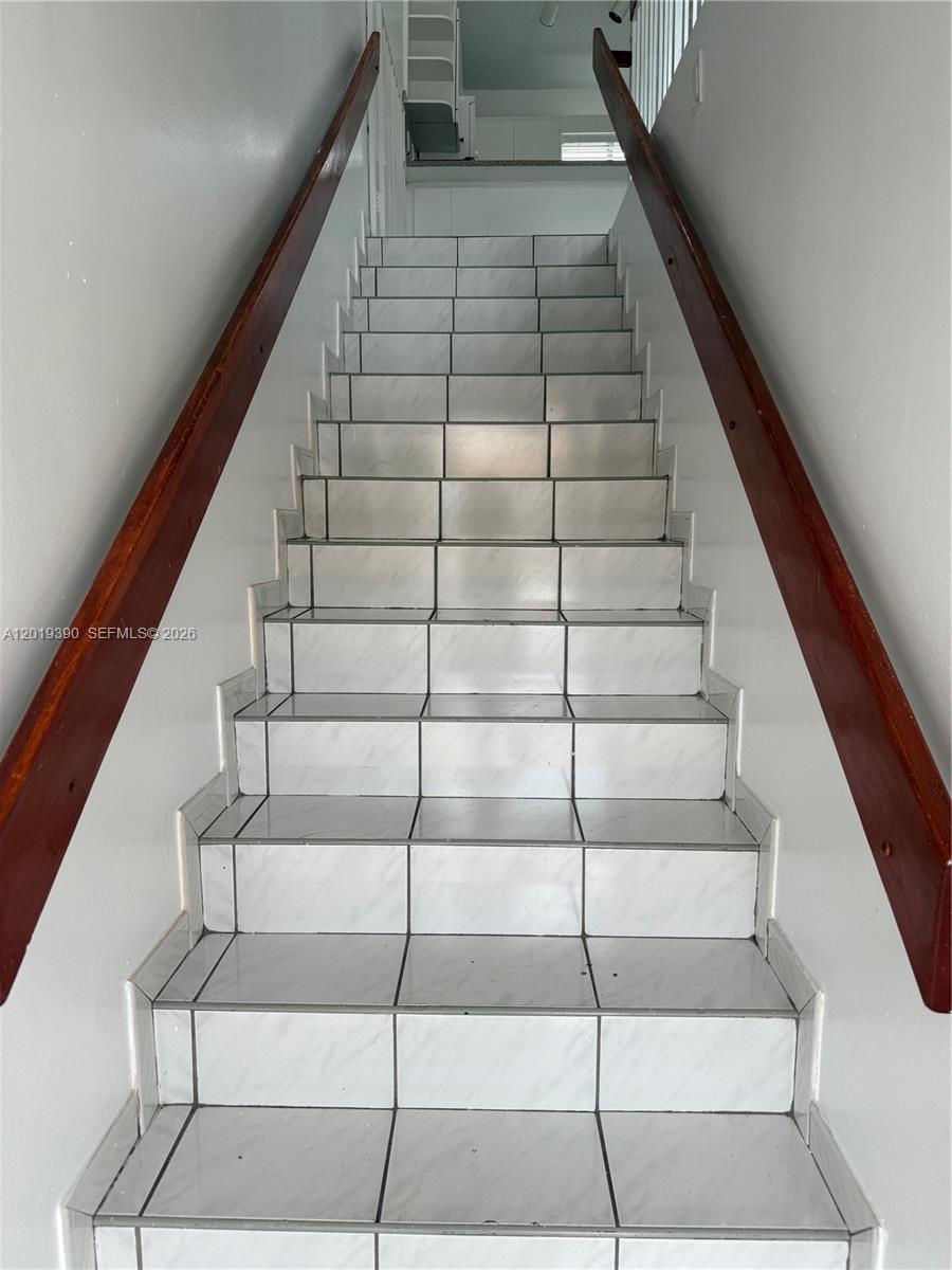 A straight staircase features white tiled steps and dark wooden handrails on both sides — 10101 W Okeechobee Rd # 9202, Hialeah Gardens FL 33016, HIALEAH GARDENS, FL