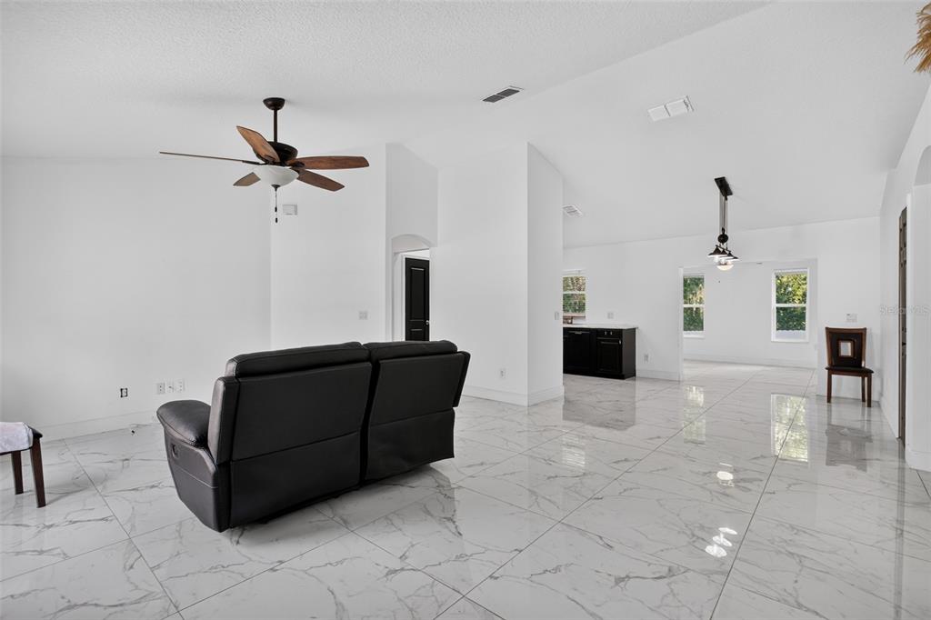 A living room with white walls, a black sofa, and white marble-patterned tile flooring — 1865 15TH STREET, ORANGE CITY, FL