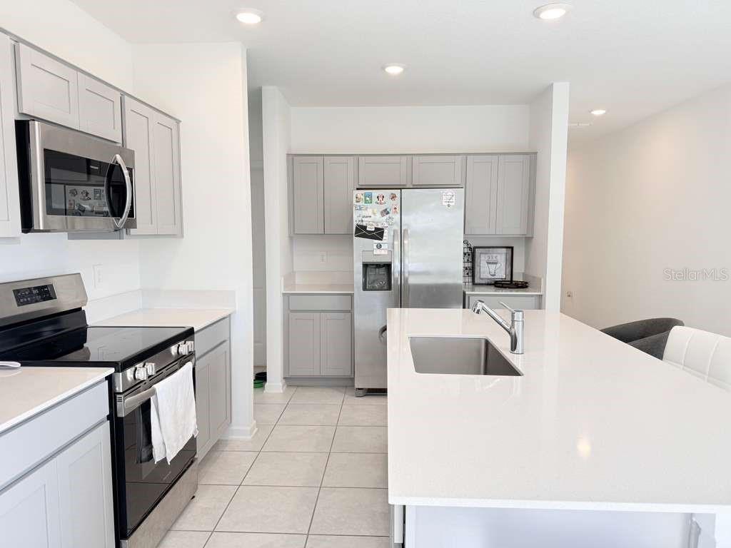 A kitchen with light gray cabinets, stainless steel appliances, and a large white quartz island — 1662 TEAGAN LANE, WINTER HAVEN, FL