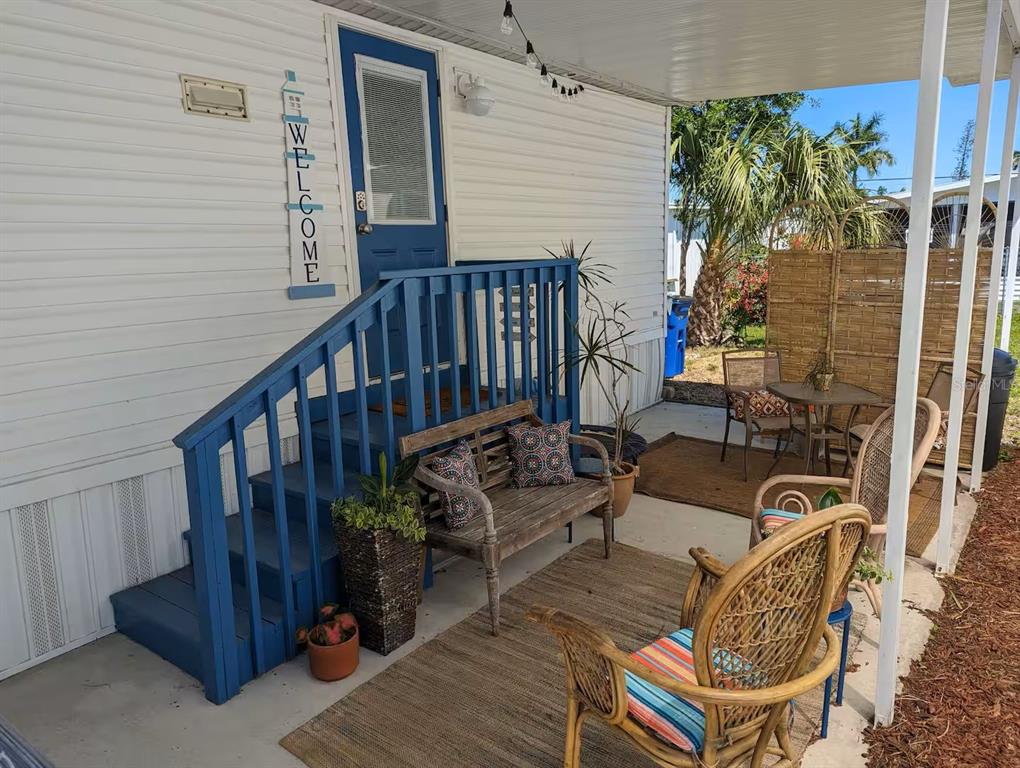 A covered patio features blue wooden stairs, wicker chairs, a bench, and a welcome sign — 12970 SPENCER STREET, FORT MYERS, FL