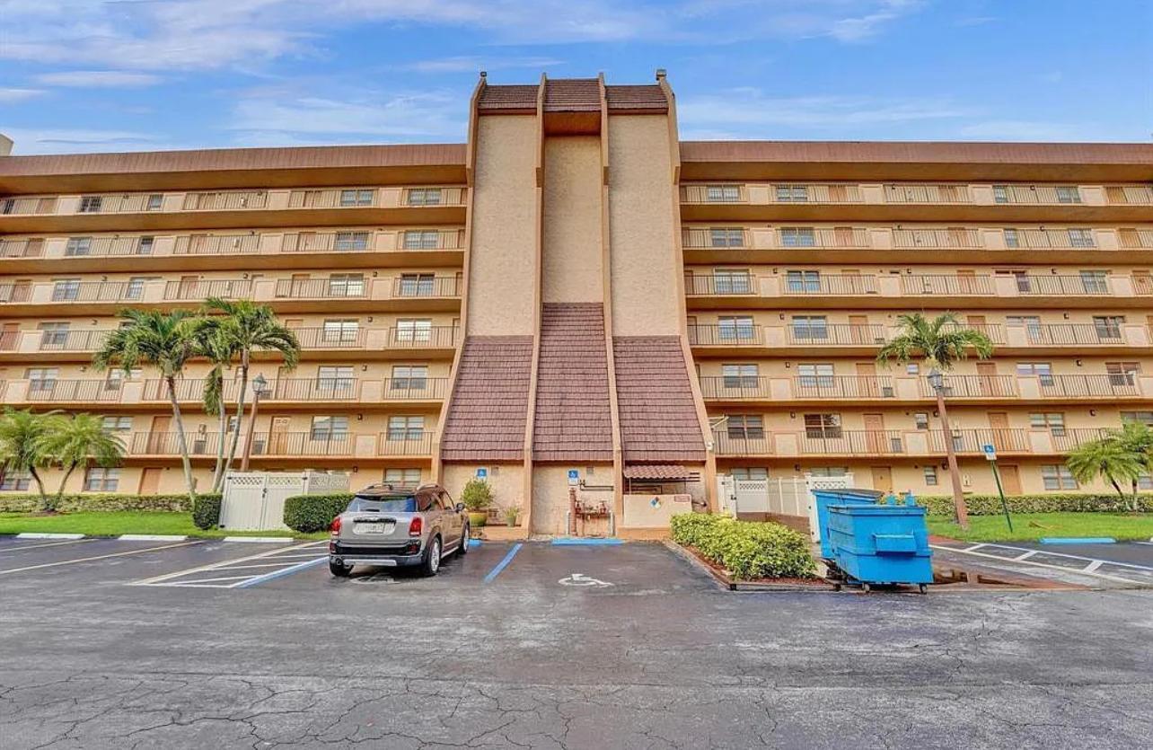 A multi-story apartment building with balconies and a central brown-tiled architectural feature above parking — 3001 W Rolling Hills # 608, Davie FL 33328, DAVIE, FL