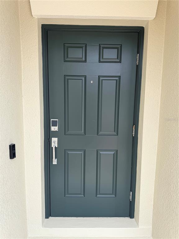 A dark green six-panel front door with a smart lock and handle set — 16491 GLASSY LOCH LOOP, CLERMONT, FL