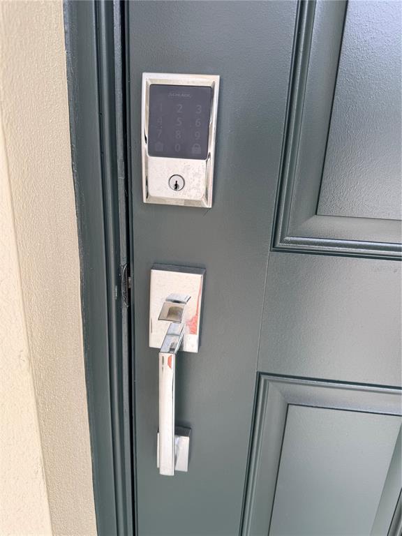 A close-up view of a dark green front door with a chrome handle and keypad — 16491 GLASSY LOCH LOOP, CLERMONT, FL