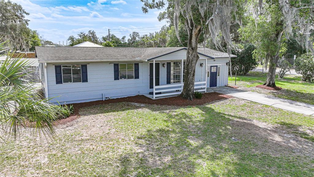 A light blue single-story house with dark shutters and a front porch sits on grass — 704 N MANATEE AVENUE, ARCADIA, FL