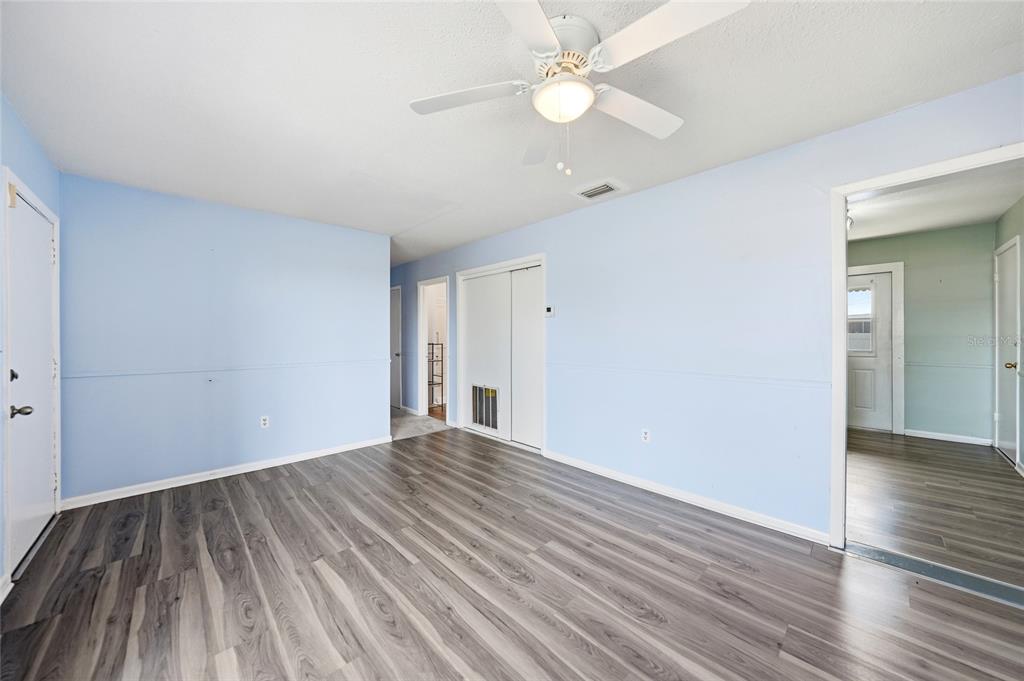A room with light blue walls, gray wood-look flooring, and a white ceiling fan — 704 N MANATEE AVENUE, ARCADIA, FL