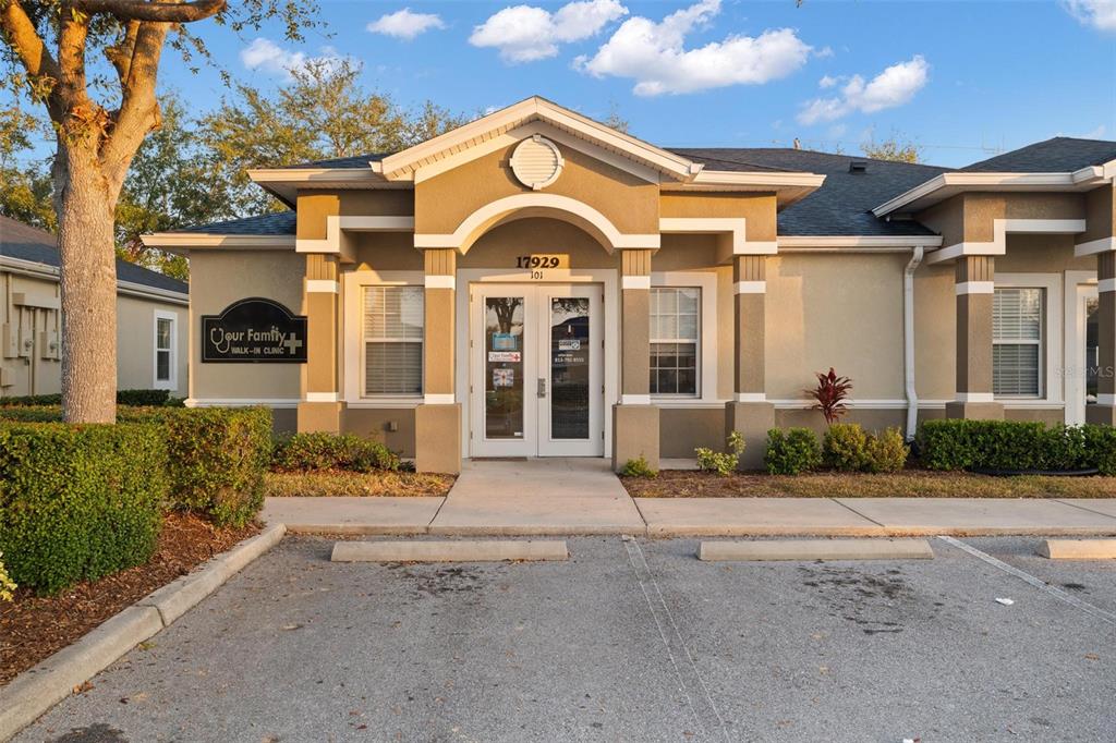 The exterior of a tan commercial building features a central entrance with double glass doors — 17929 HUNTING BOW CIRCLE UNIT 101 & 102, LUTZ, FL