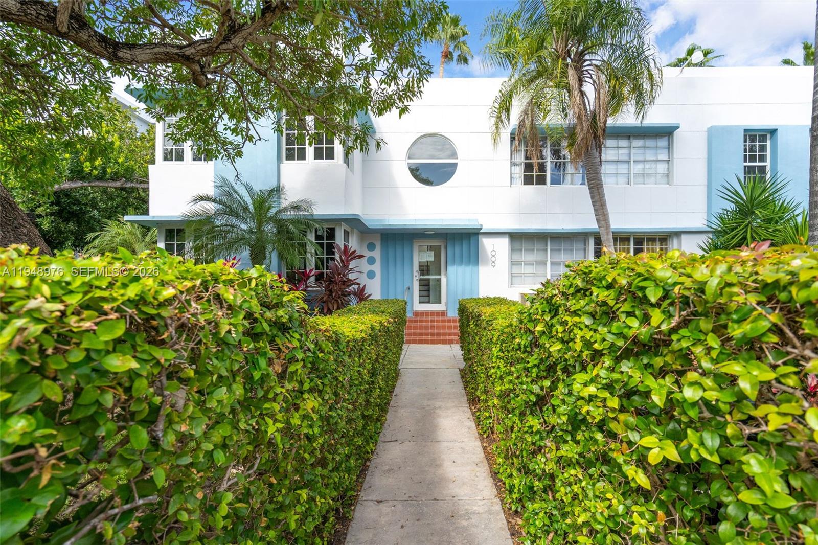 A two-story white building with blue accents features a circular window and a hedged walkway — 1009 Meridian Ave # 15, Miami Beach FL 33139, MIAMI BEACH, FL