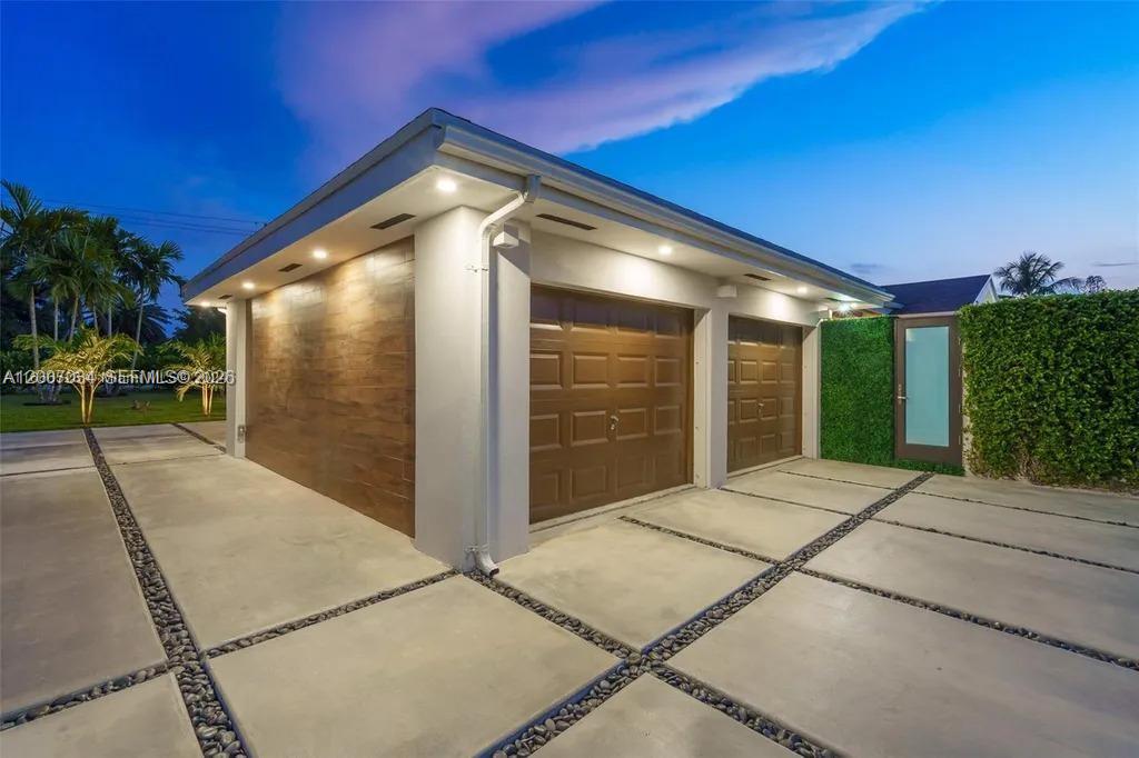 A modern garage exterior features wood-paneled walls, two brown doors, and a concrete driveway — 13540 SW 98th Ct, Miami FL 33176, MIAMI, FL