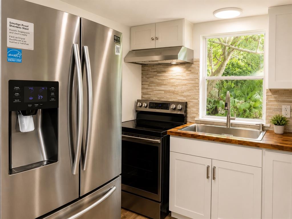 A kitchen features stainless steel appliances, white cabinets, a wood countertop, and a window — 8010 W MORROW COURT, CRYSTAL RIVER, FL