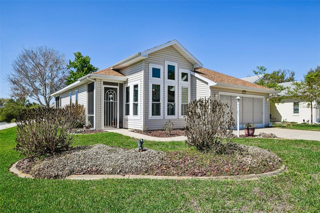 A single-story house with light-colored siding, a front porch, and a two-car garage — 6105 DORY WAY, TAVARES, FL