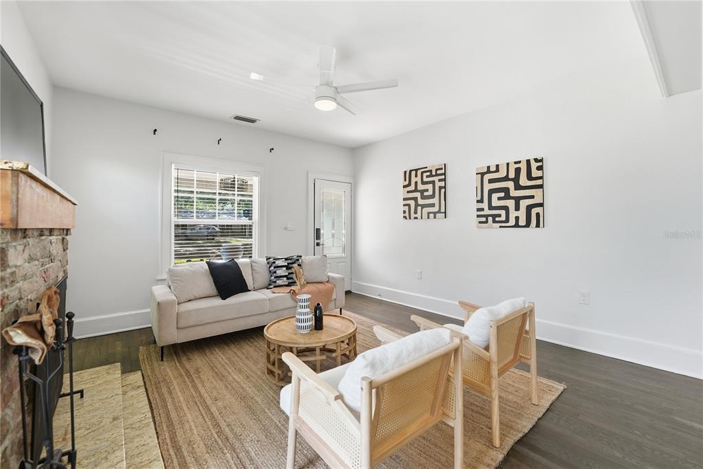 A living room features a brick fireplace, light-colored sofa, two wooden chairs, and hardwood floors — 204 N BROWN AVENUE, ORLANDO, FL