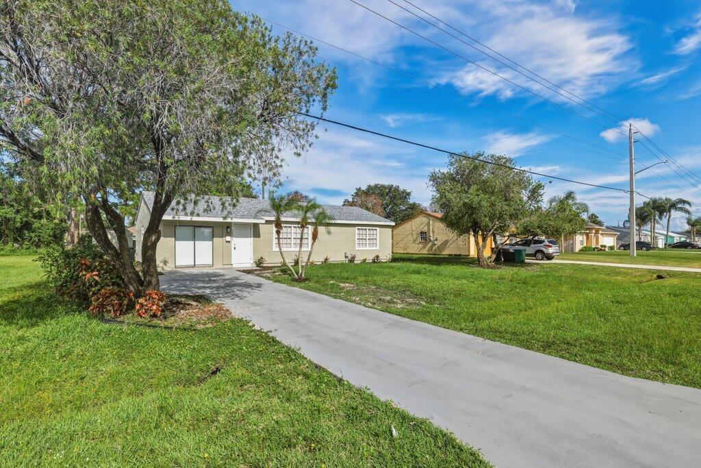 A single-story house with a concrete driveway and a large tree in the front yard — 2521 SE Berkshire Boulevard, FL 34952, FL
