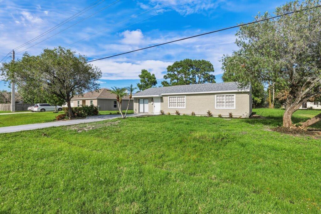 A single-story house with a light-colored exterior, a driveway, and a large front lawn — 2521 SE Berkshire Boulevard, FL 34952, FL