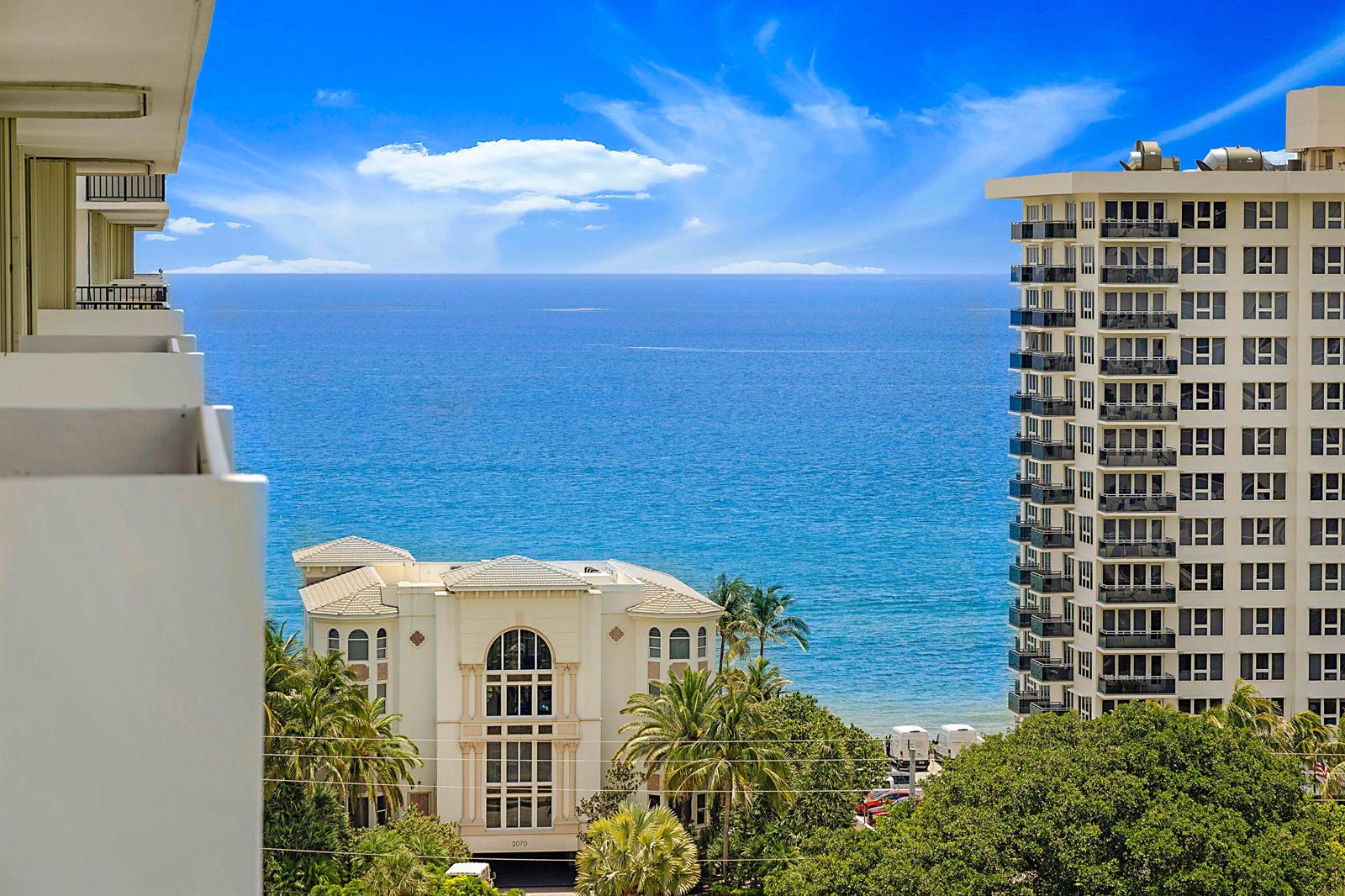 An elevated view of the ocean, palm trees, and neighboring high-rise buildings from a balcony — 2121 N Ocean Boulevard # 1507w, Boca Raton FL 33431, BOCA RATON, FL