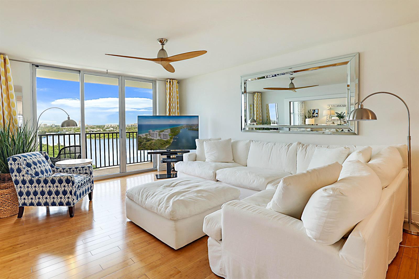 A living room features a white sectional sofa, patterned armchair, and balcony with water views — 2121 N Ocean Boulevard # 1507w, Boca Raton FL 33431, BOCA RATON, FL