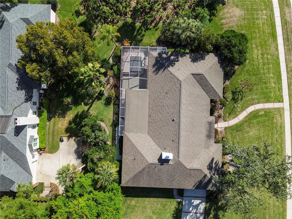 An aerial view shows a house with a screened-in pool enclosure and a shingled roof — 10002 HUNT CLIFF DRIVE, RIVERVIEW, FL