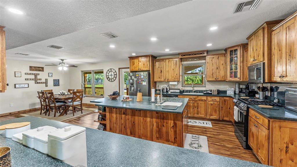 A kitchen with wood cabinets, a large island, and an adjacent dining area — 339 MINI RANCH ROAD, SEBRING, FL