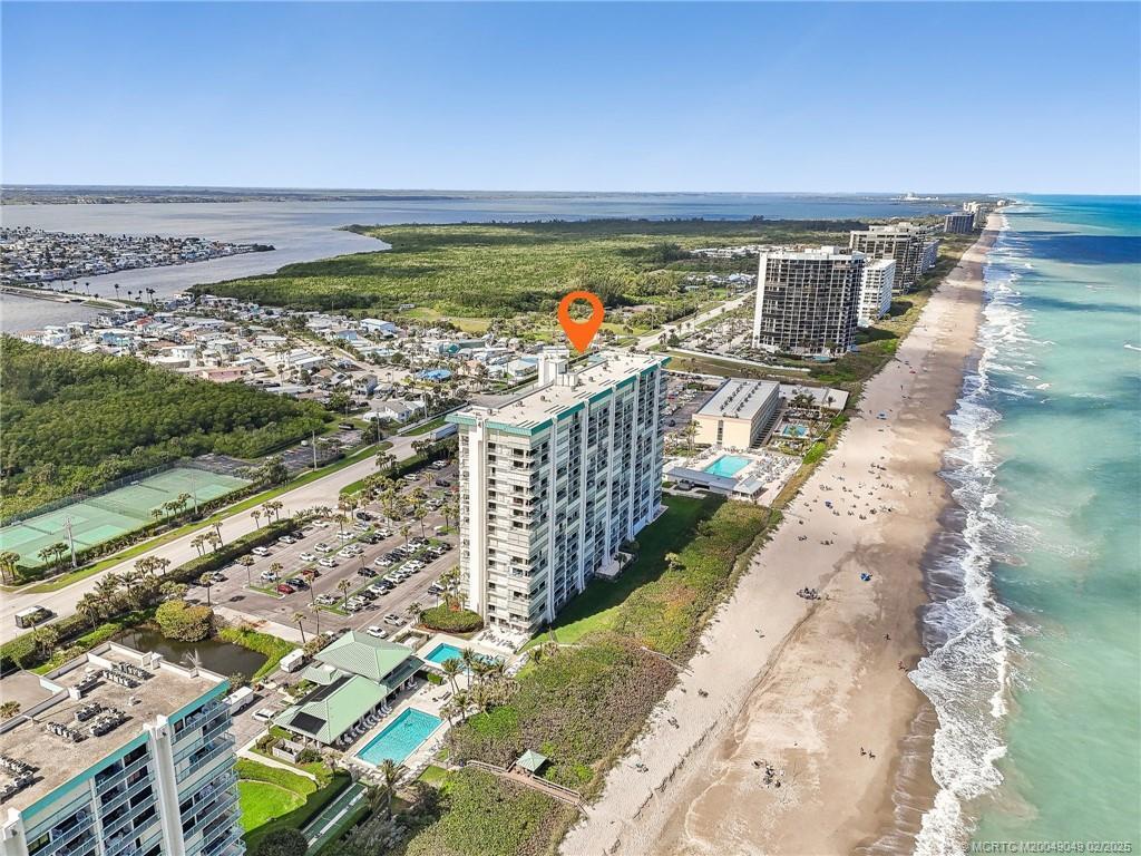 An aerial view shows a high-rise condominium building situated directly on a sandy beach — 9900 S Ocean Drive # 804, Jensen Beach FL 34957, JENSEN BEACH, FL