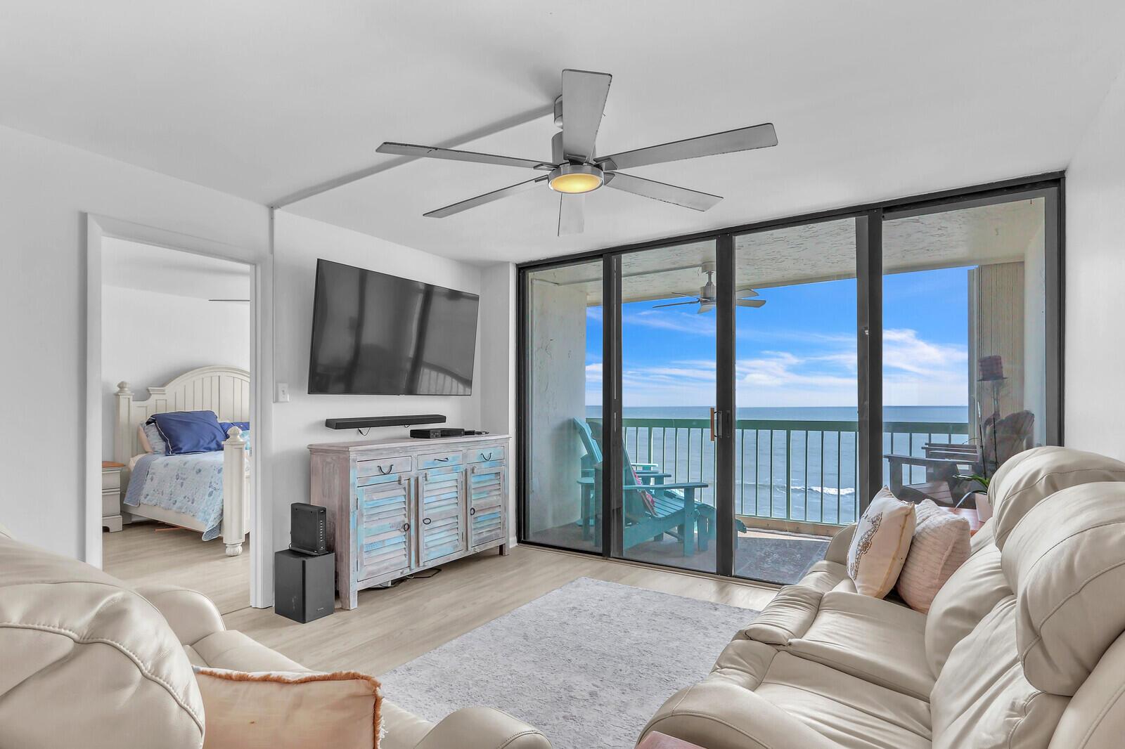 A balcony with a green railing overlooks the ocean under a blue, cloudy sky — 9900 S Ocean Drive # 804, Jensen Beach FL 34957, JENSEN BEACH, FL