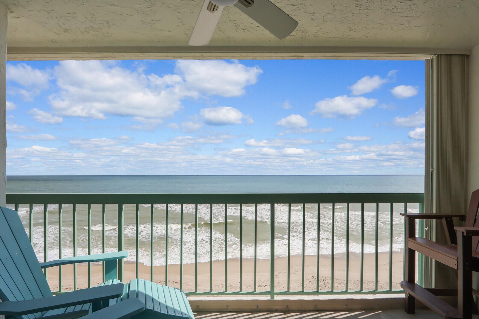 A balcony with chairs overlooks a sandy beach and the ocean under a cloudy sky — 9900 S Ocean Drive # 804, Jensen Beach FL 34957, JENSEN BEACH, FL