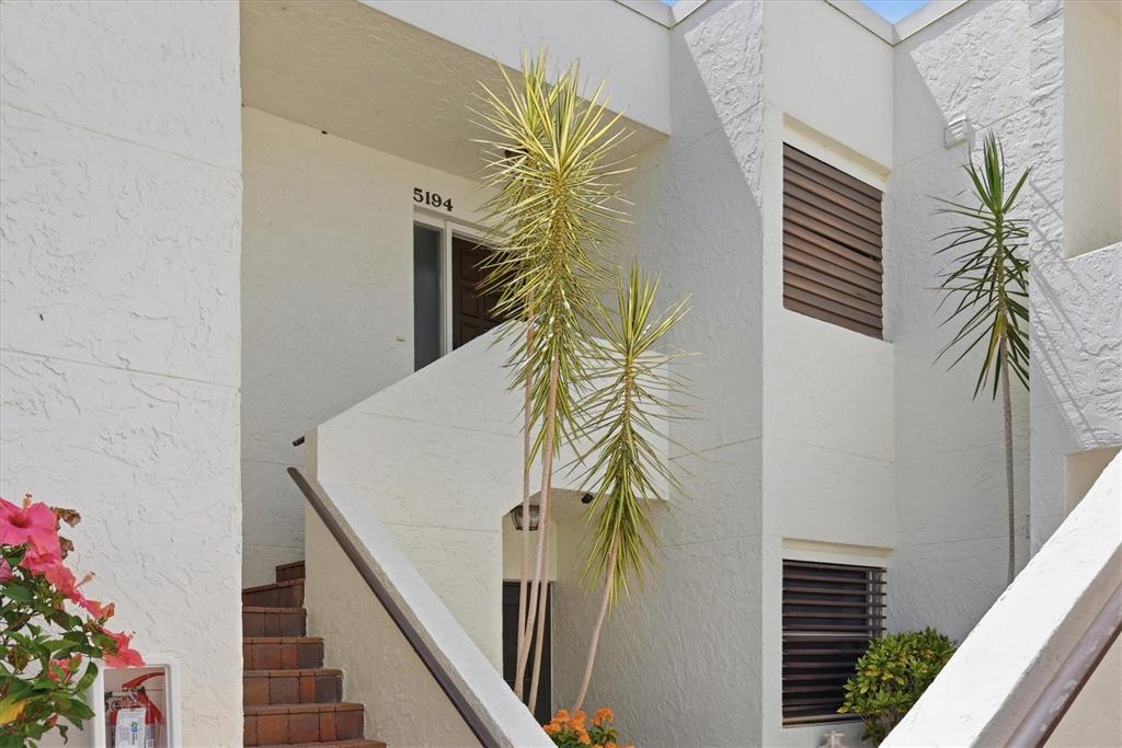 An exterior view of a white stucco building with a staircase leading to an entrance — 5194 MARSH FIELD LANE UNIT 96, SARASOTA, FL