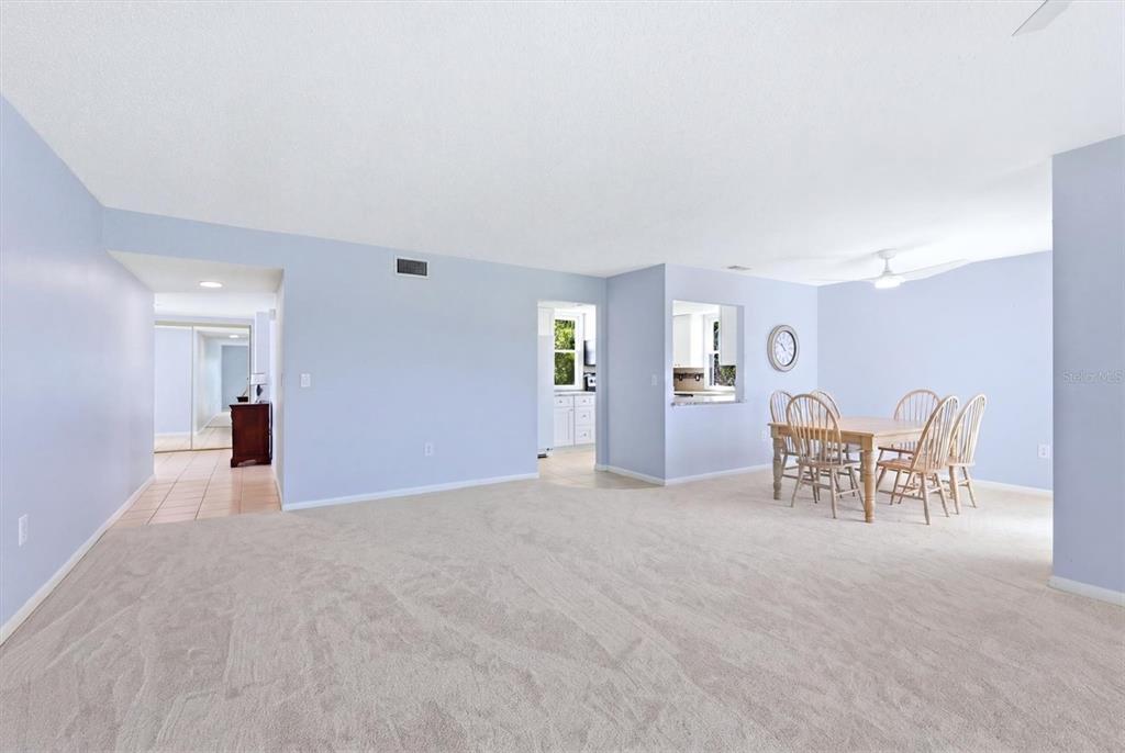 A spacious living and dining area with light blue walls and beige carpeting — 5194 MARSH FIELD LANE UNIT 96, SARASOTA, FL