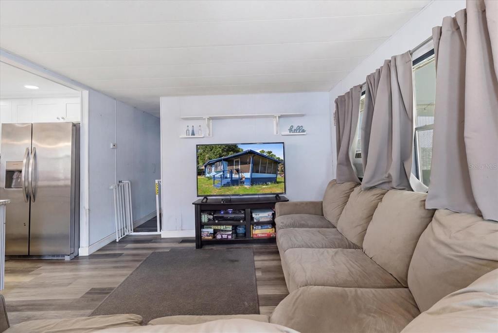 A living room features a sectional sofa, a television on a stand, and wood-look flooring — 4610 E AMHERST STREET, HERNANDO, FL