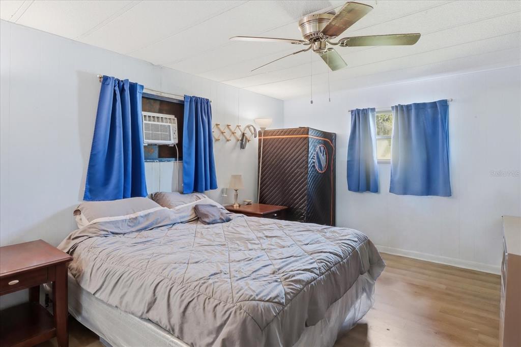 A bedroom features a bed, a ceiling fan, blue curtains, and a portable sauna unit — 4610 E AMHERST STREET, HERNANDO, FL