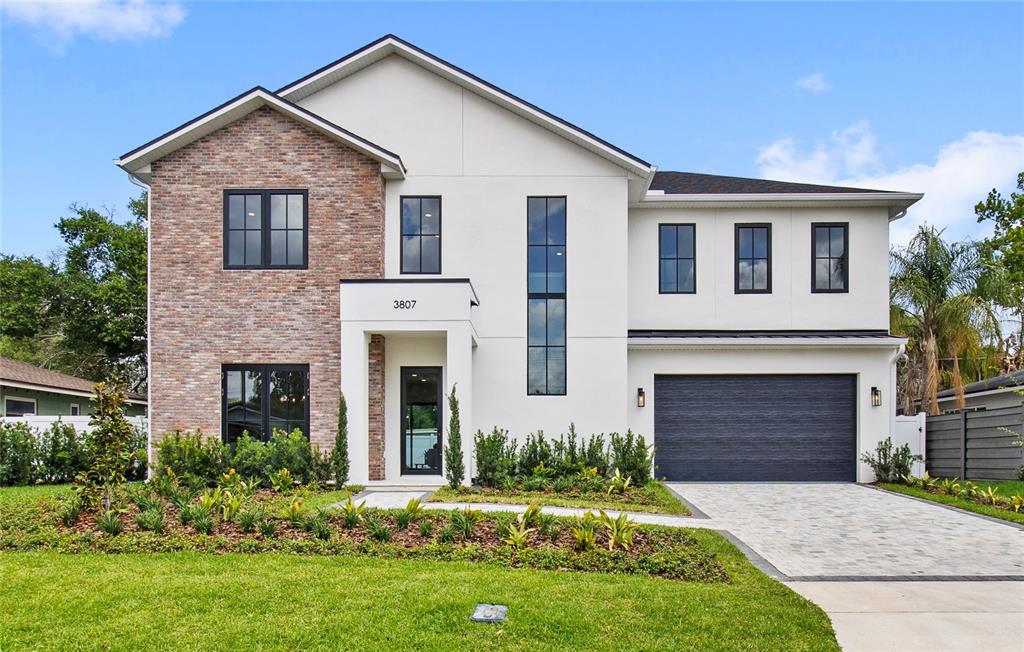 A two-story house features a brick facade, white stucco walls, and a dark garage door — 3807 PELICAN LANE, ORLANDO, FL
