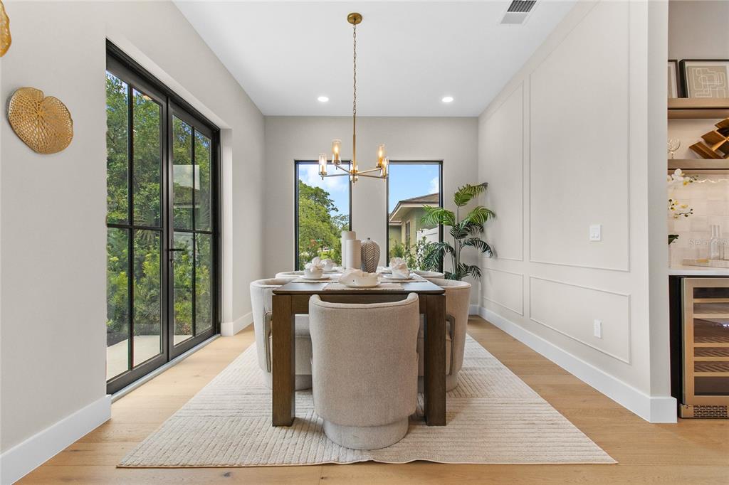 A dining room features a wooden table, upholstered chairs, a chandelier, and glass patio doors — 3807 PELICAN LANE, ORLANDO, FL