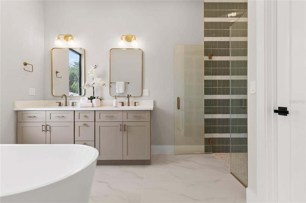 A modern bathroom features a double vanity, a freestanding tub, and a glass-enclosed walk-in shower — 3807 PELICAN LANE, ORLANDO, FL