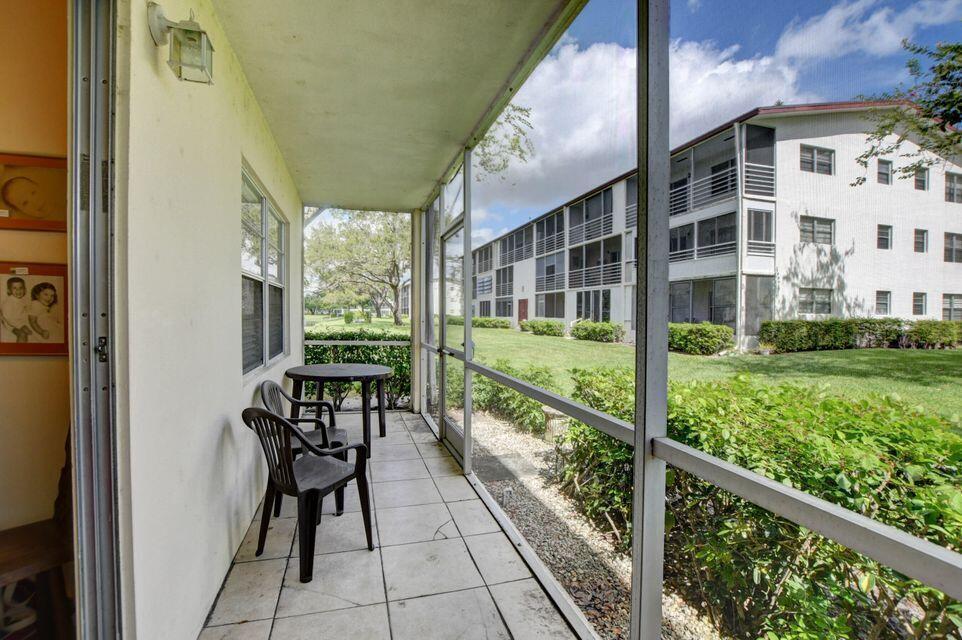 A grassy lawn leads to a pond in front of multi-story apartment buildings under clouds — 137 Fanshaw D, Boca Raton FL 33434, BOCA RATON, FL