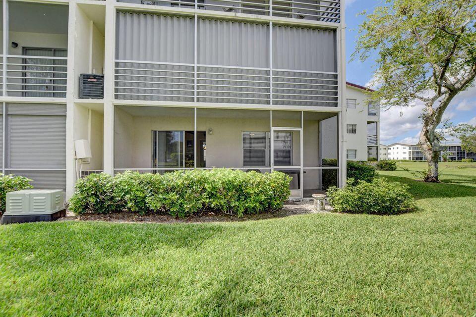 An exterior walkway leads to a red-framed door and a window with gray blinds — 137 Fanshaw D, Boca Raton FL 33434, BOCA RATON, FL
