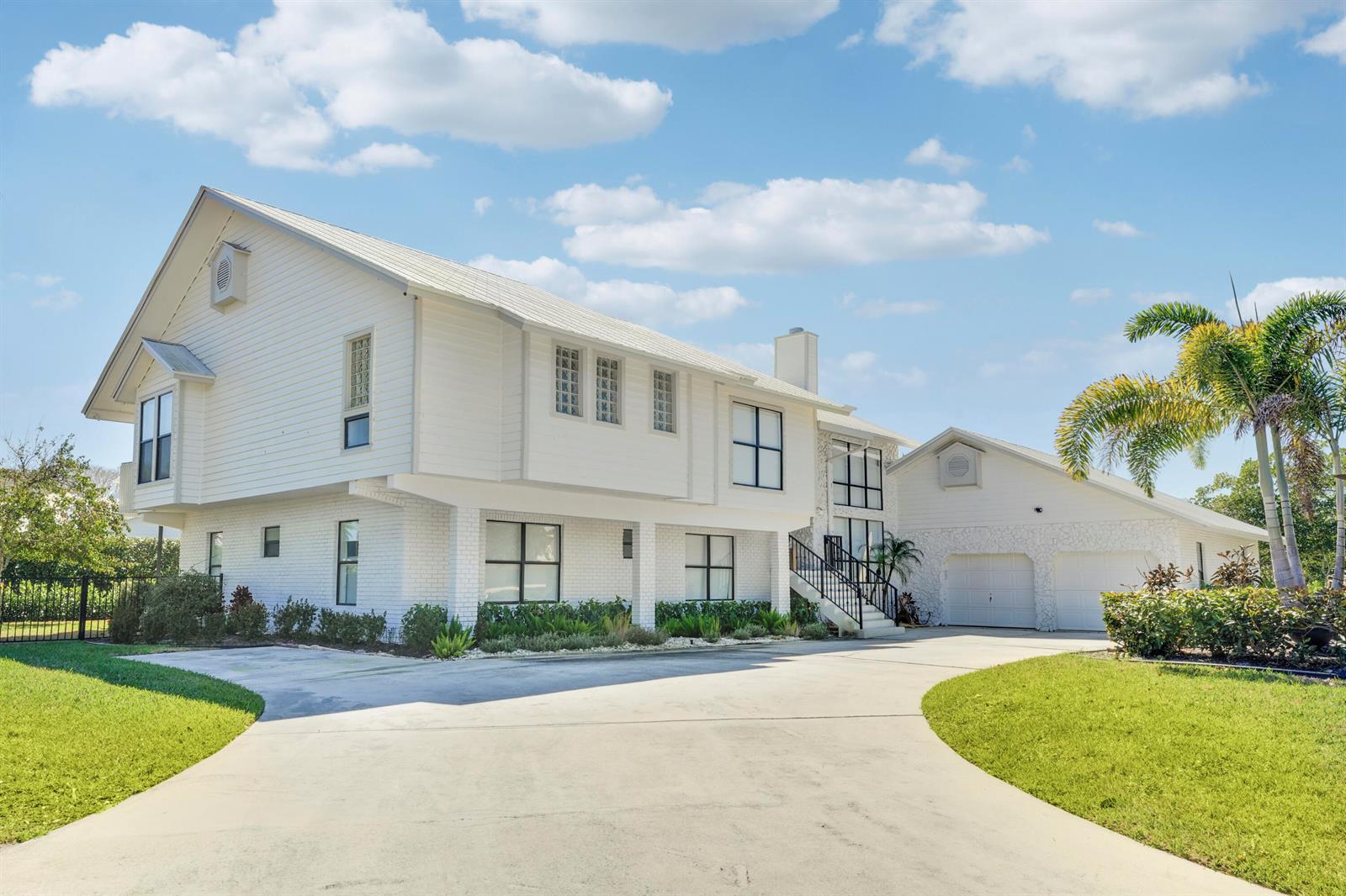 A two-story white house with a brick base, attached garage, and a concrete driveway — 4290 SE Whiticar Way, Stuart FL 34997, STUART, FL