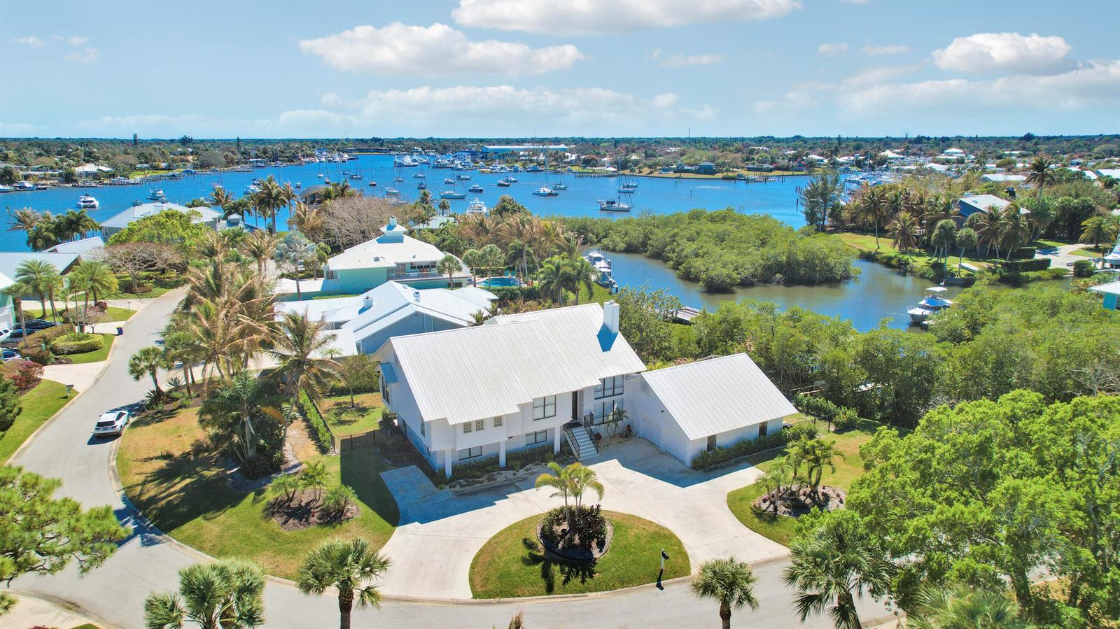 An aerial view shows a white house with a metal roof near a waterway — 4290 SE Whiticar Way, Stuart FL 34997, STUART, FL