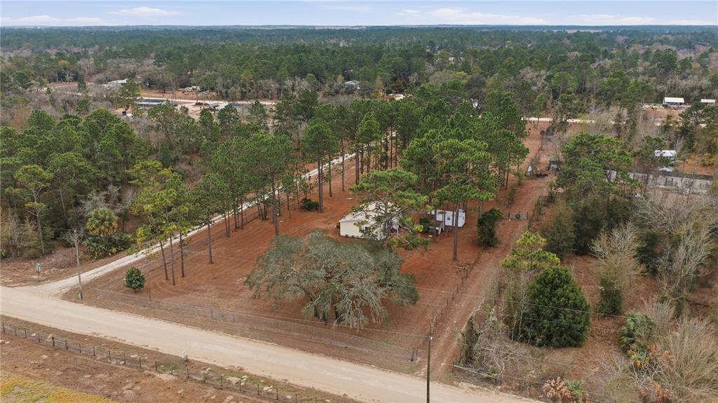 An aerial view shows a house situated on a large, wooded lot with a dirt road — 2090 SE 133RD COURT, MORRISTON, FL