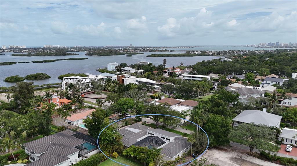 An aerial view shows a single-story house with a screened-in pool and a gray roof — 1428 PINE BAY DRIVE, SARASOTA, FL
