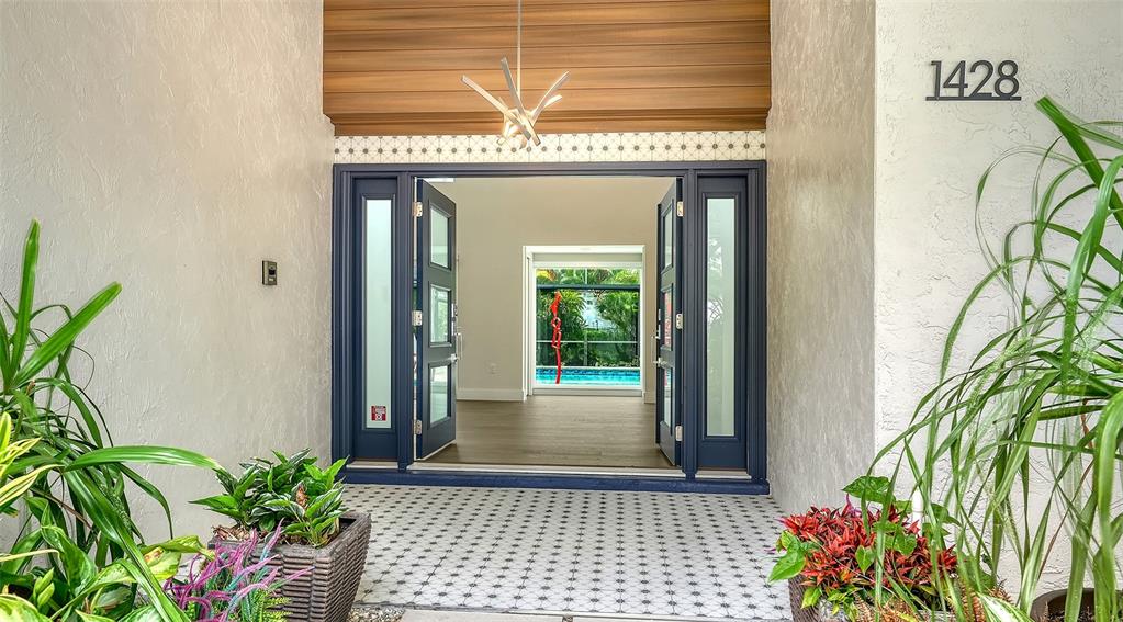 An open double door reveals a view through a home to a backyard swimming pool — 1428 PINE BAY DRIVE, SARASOTA, FL