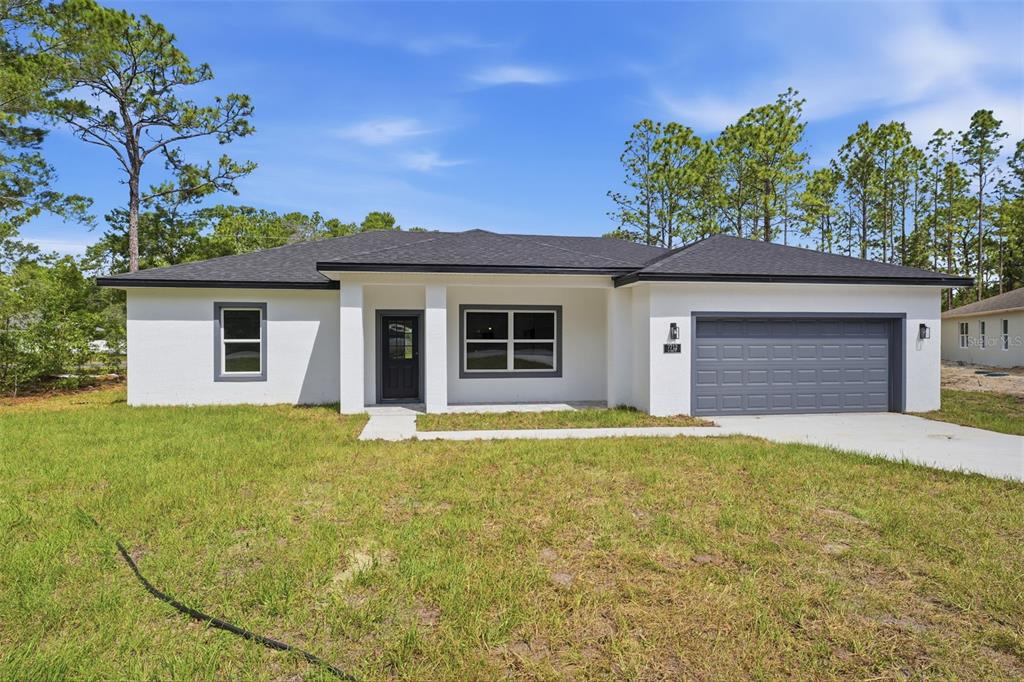 A single-story white house with a dark gray roof and a two-car garage — 7712 N TIDE POINT, CITRUS SPRINGS, FL